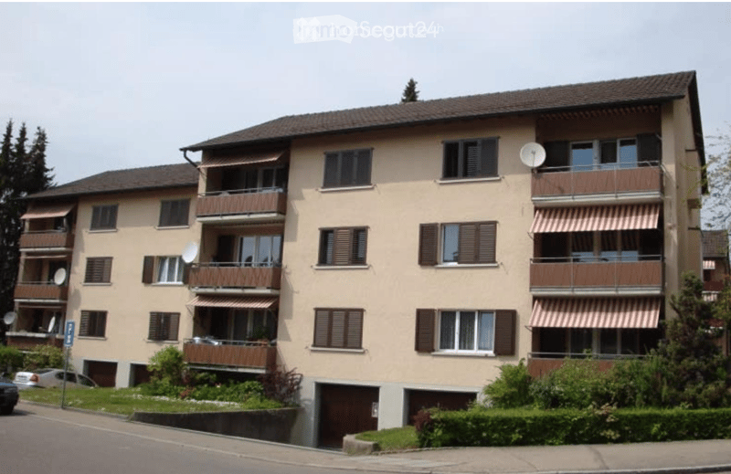 Four-story residential building with balconies, satellite dishes, and a garage entrance.