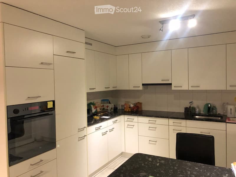 Modern kitchen with white cabinets, black granite countertop, built-in oven, and various appliances.