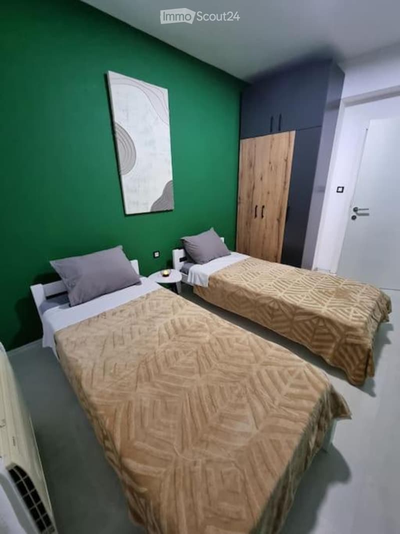 Cozy bedroom with two single beds, matching bedspreads, nightstand, wardrobe, and a decorative picture frame on the wall.