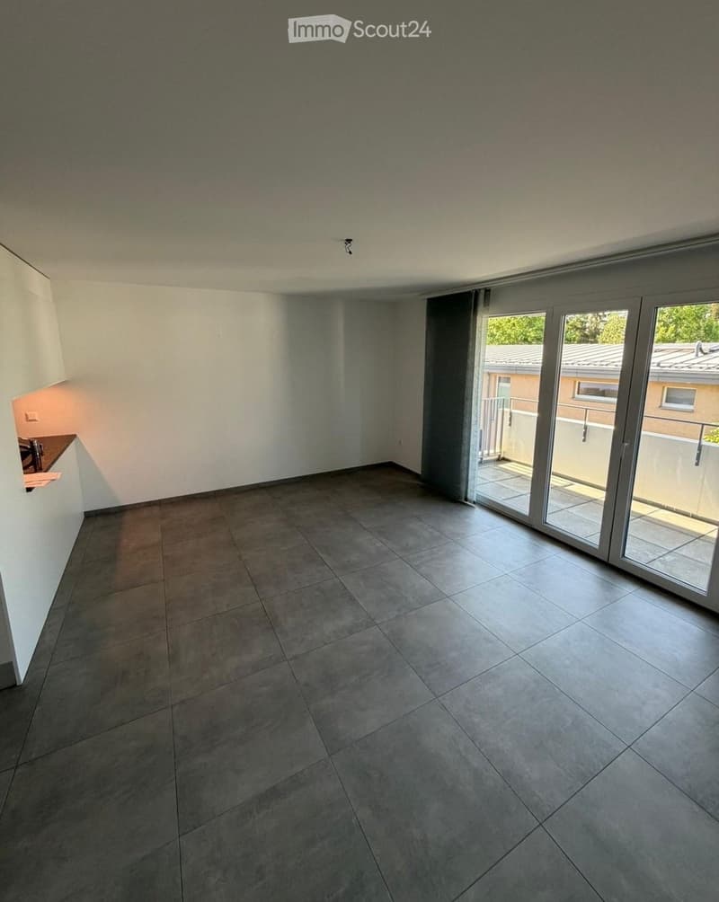 Empty room with tiled floor, white walls, and large sliding glass doors leading to a balcony.