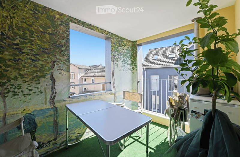 Balcony with a view of the city, featuring a table, chairs, and a refrigerator.