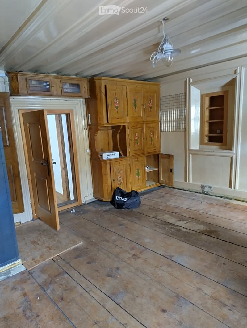 Empty room with wooden floor, wooden cabinets, and a chandelier. No furniture or equipment.