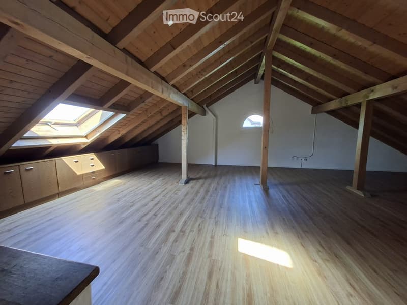 Empty attic space with wooden beams, wooden flooring, built-in cabinets, skylight windows, and exposed wooden beams.