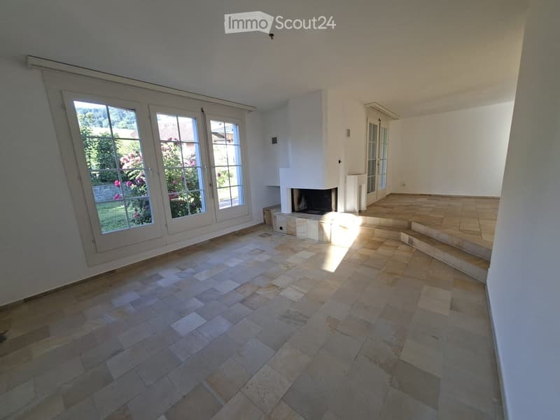 Empty room with tiled flooring, large windows, and a fireplace. No furniture or equipment present.