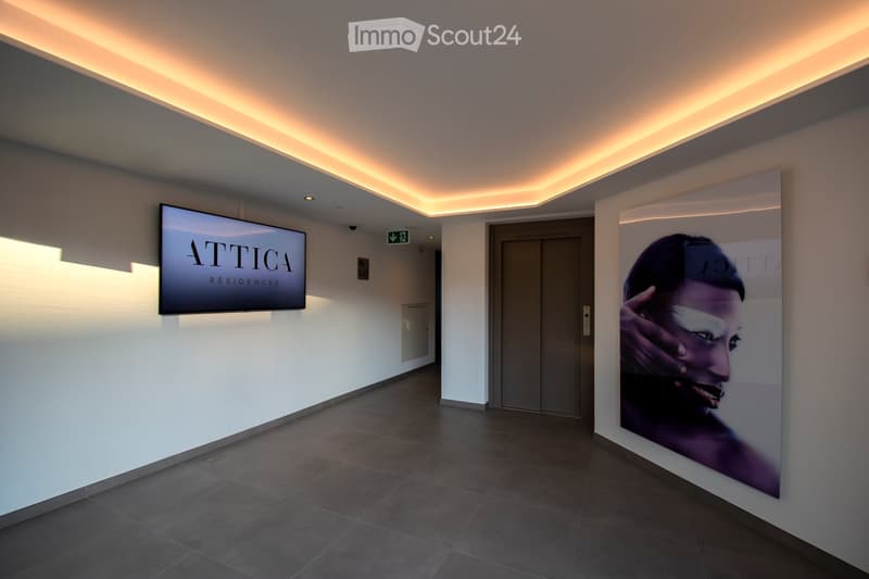 Modern hallway with sleek lighting, elevator, and wall-mounted screens displaying branding.