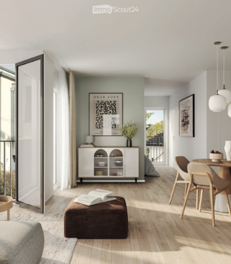 Modern living room with light wood flooring, a grey sofa, a brown ottoman with books, a small wooden table with chairs, a white cabinet with glass doors, and a vase with flowers on the cabinet.