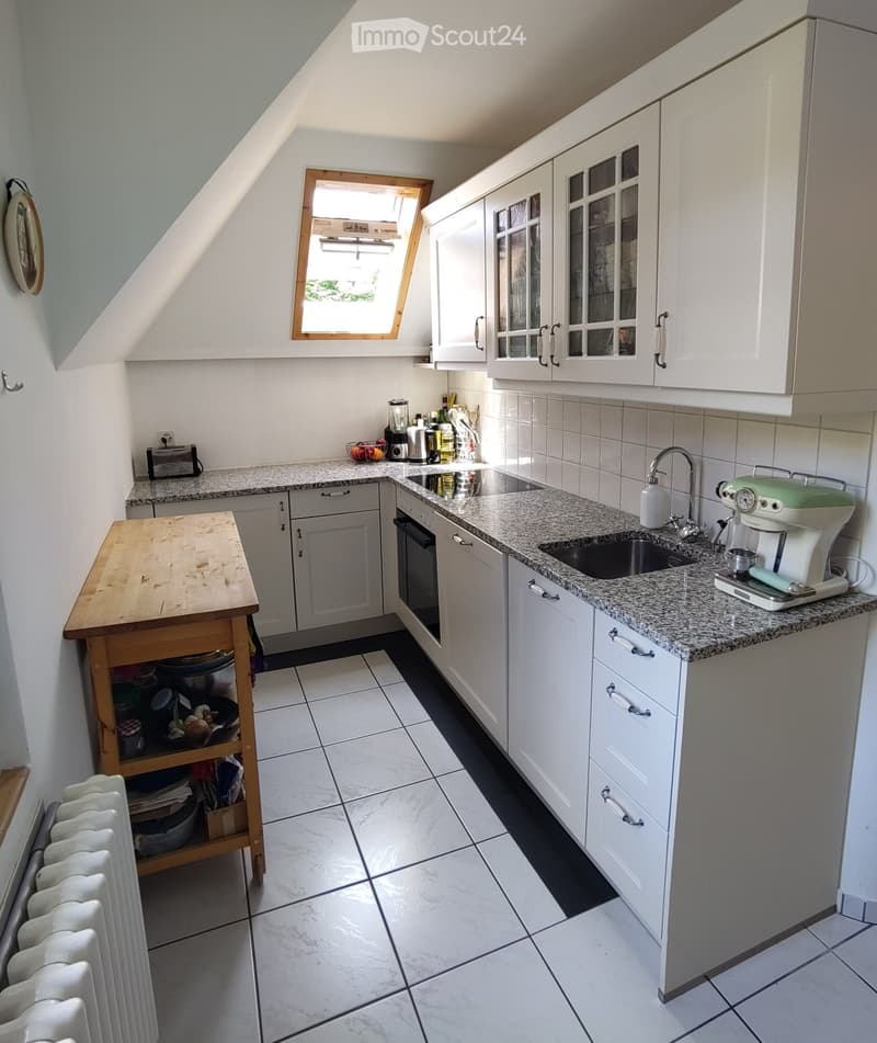 Bright kitchen with white cabinets, granite countertops, and a wooden cutting board. Features a sink, coffee maker, and various appliances.