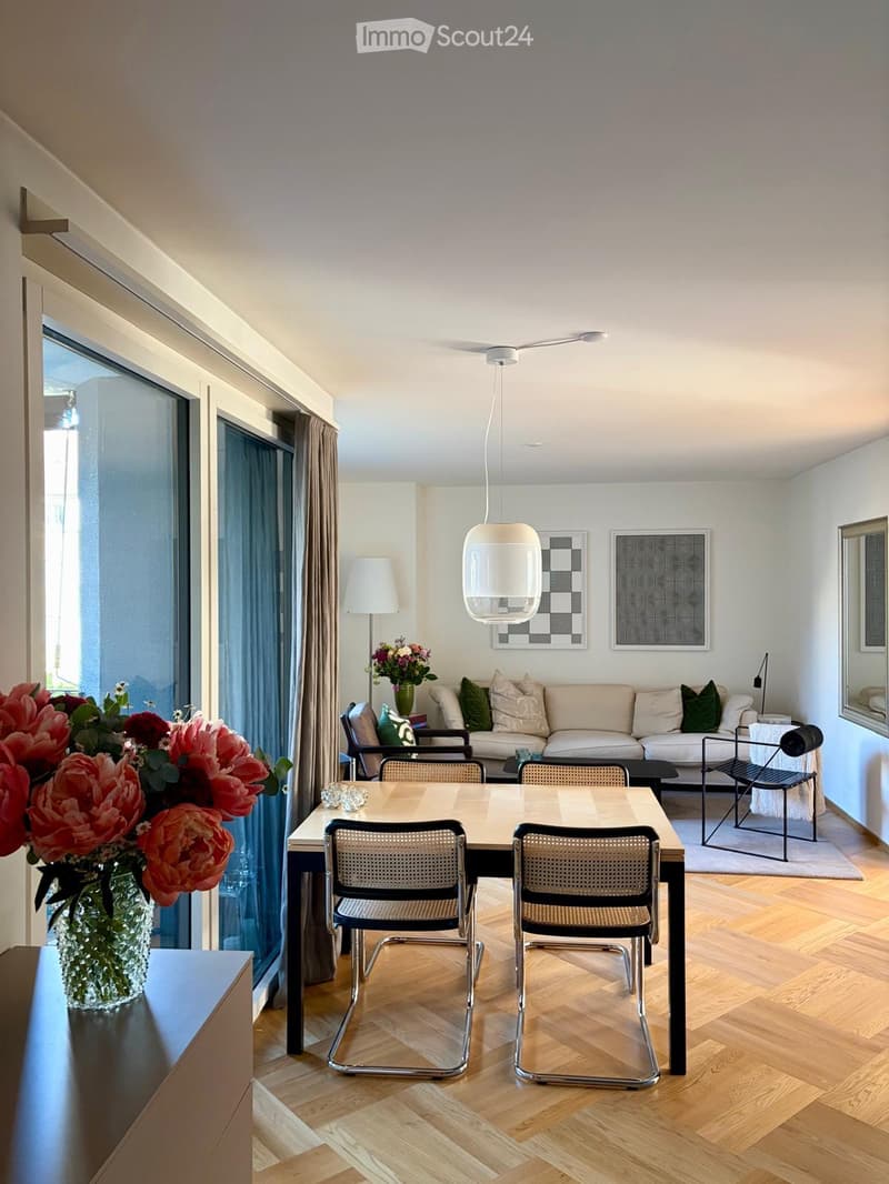 Modern living and dining area with light-colored sofa, coffee table, dining table with chairs, and decorative vases.