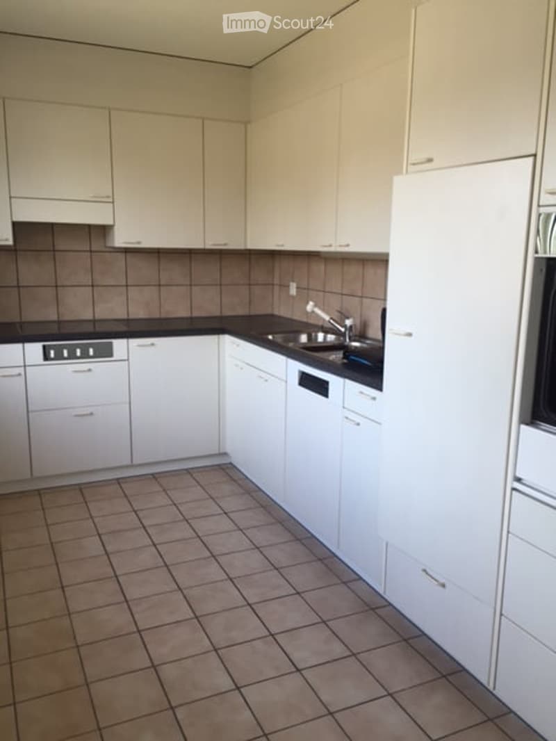 Modern kitchen with white cabinets, black countertops, and tiled flooring. Includes a sink, faucet, oven, and dishwasher.