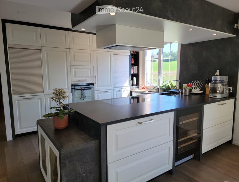 Modern kitchen with white cabinets, black countertops, stainless steel appliances, and a central island.