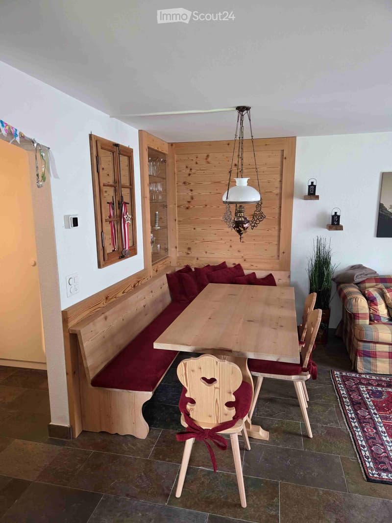 Cozy dining area with wooden bench seating, a table, chairs, a cabinet, and a pendant light.