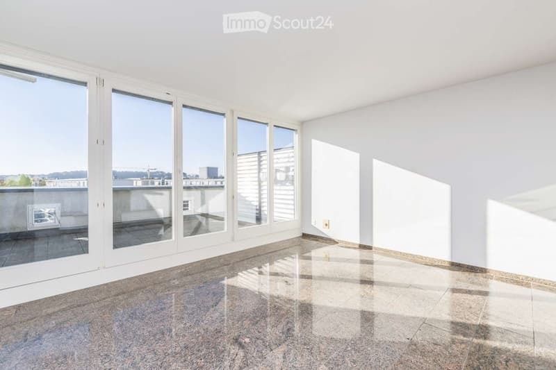 Empty room with large windows and a view of a balcony area. The floor is tiled, and the walls are white.