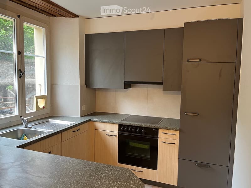 Modern kitchen with light wood cabinets, granite countertops, stainless steel sink, and built-in oven.