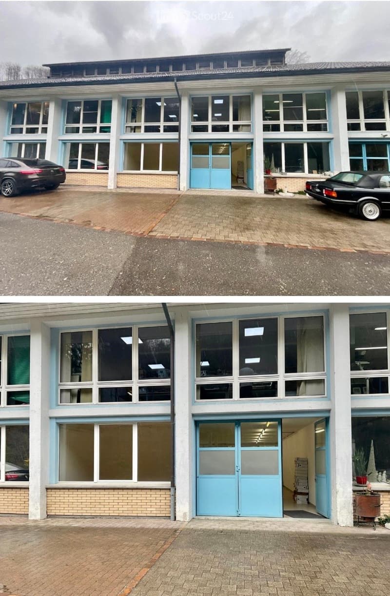 Two-story building with large windows, light blue doors, and a garage entrance. Two black cars are parked in front.