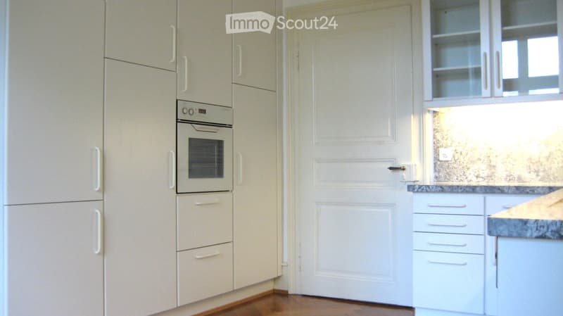 Modern kitchen with white cabinets, built-in oven, and granite countertop.