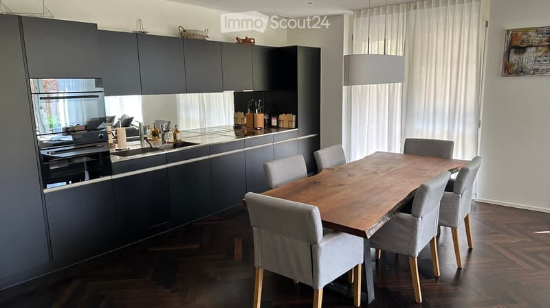 modern kitchen with dining area, wooden table, gray chairs, black cabinets, white curtains, wooden floor