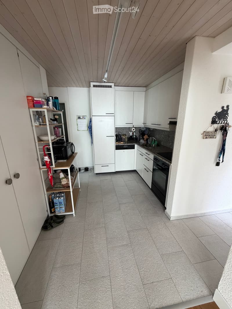 Modern kitchen with white cabinets, tiled floor, and various appliances including a refrigerator, oven, microwave, and sink.