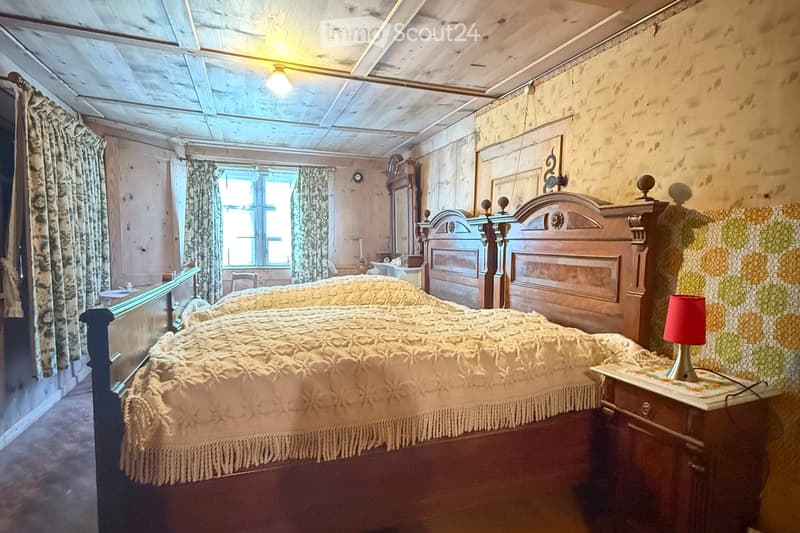 two wooden beds, nightstand, small lamp, patterned wallpaper, curtains, vintage furniture