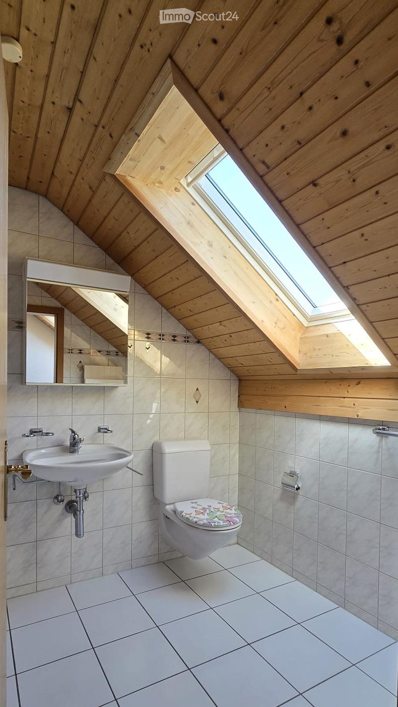 Bathroom with white tiles, white sink, white toilet, mirror, wooden ceiling, skylight
