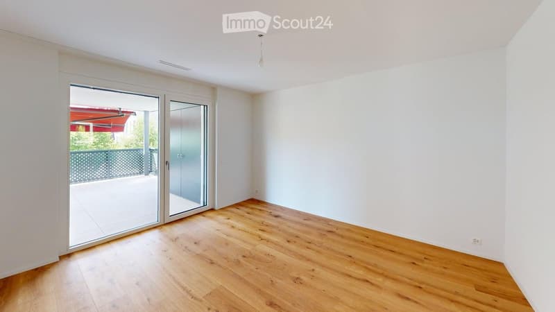 Empty room with wooden flooring, white walls, and large sliding glass doors leading to a balcony or terrace.