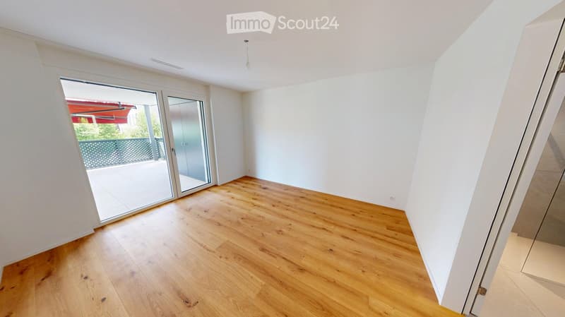 Empty room with wooden flooring, white walls, and large sliding glass doors leading to a balcony.