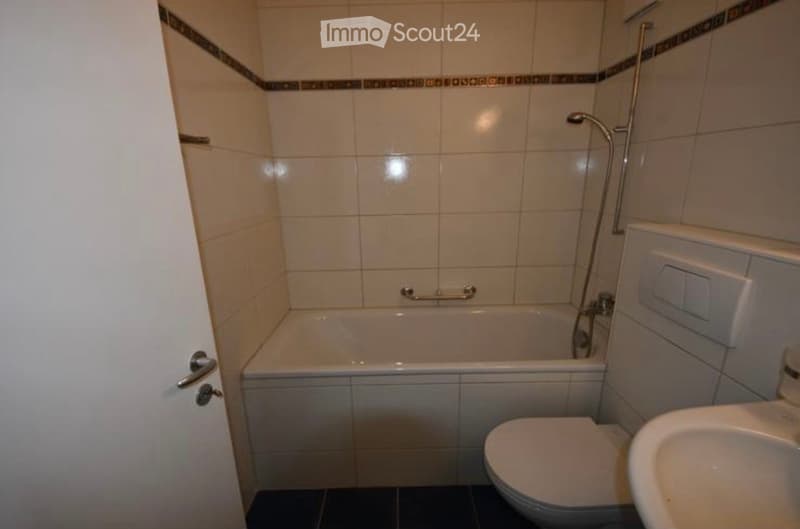Bathroom with a bathtub, toilet, sink, and tiled walls.