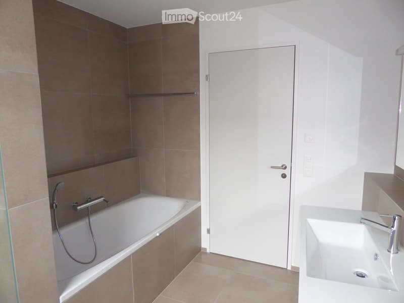 Bathroom. Modern bathroom with a bathtub, a sink, and a glass shower enclosure. The walls are tiled in neutral tones, and the floor is tiled in beige.