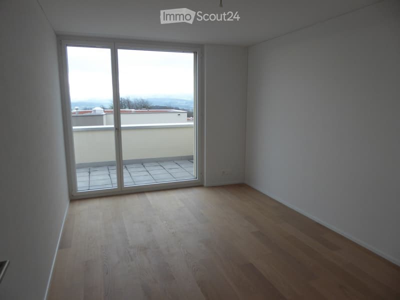 Unfurnished Room. Empty room with wooden flooring and large sliding glass doors leading to a balcony with a view of the landscape.