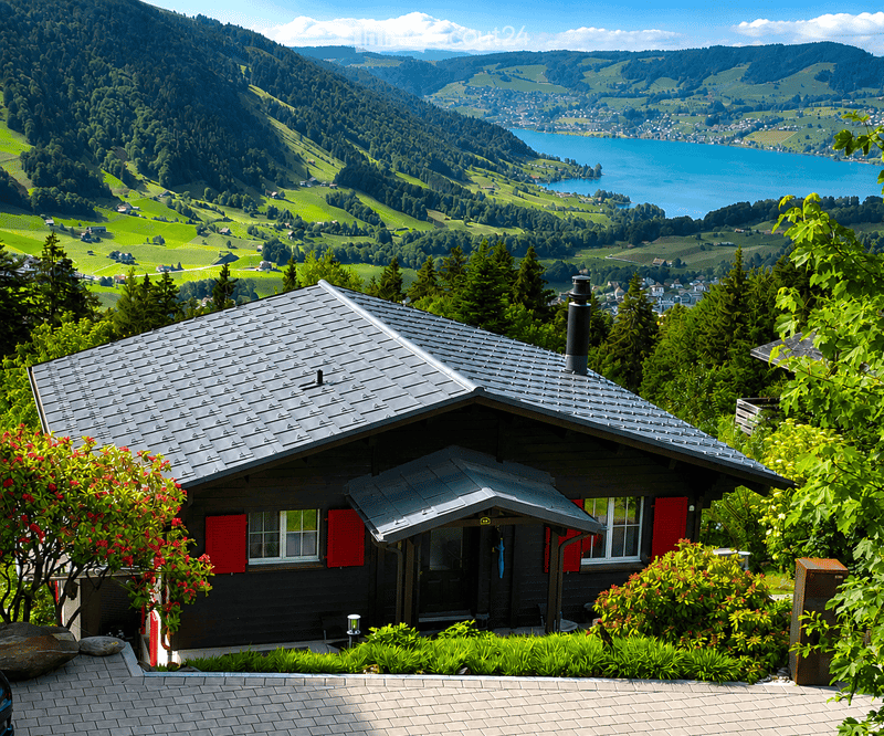 Traditional wooden house with red shutters, surrounded by lush greenery and offering a scenic mountain and lake view.