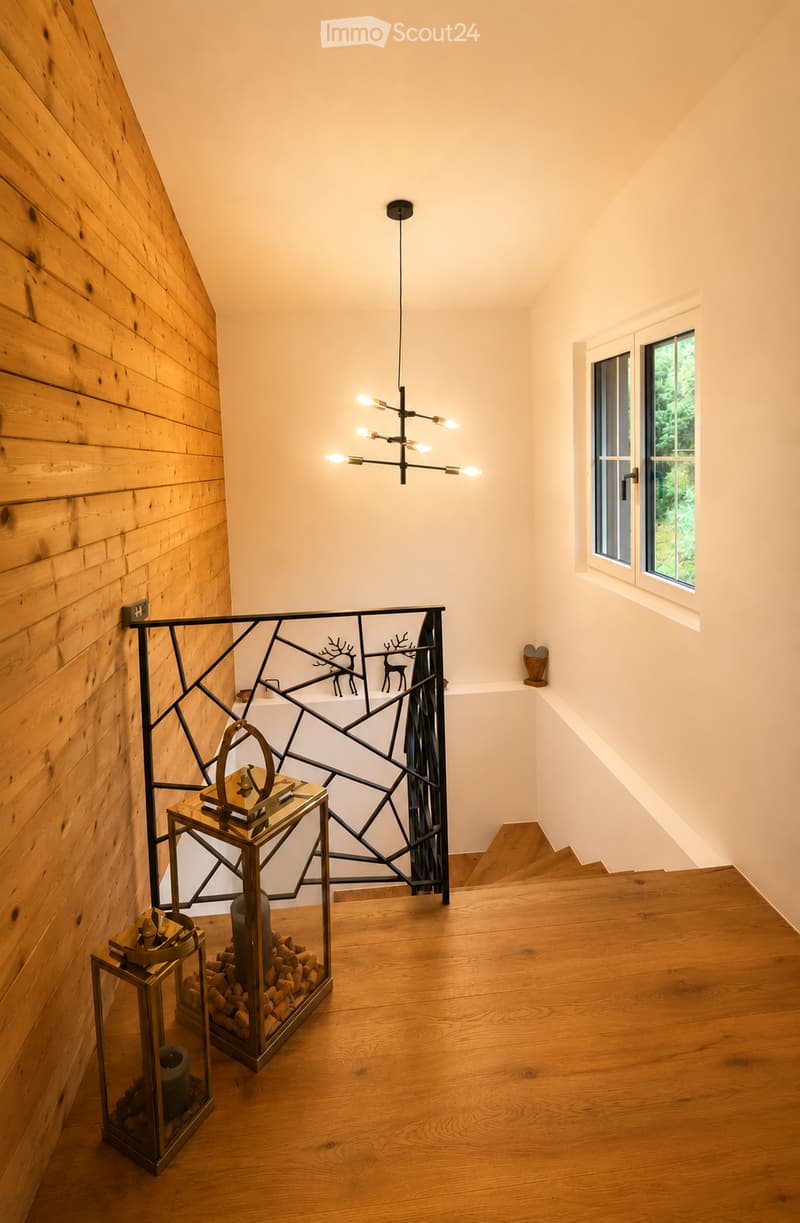 Staircase with wooden steps, modern railing, pendant light fixture, and decorative lanterns on the landing.