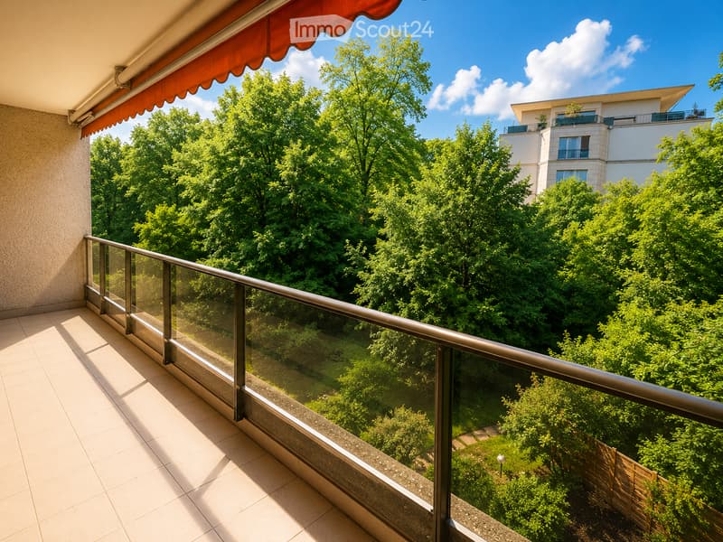 Balcony with glass railing, tiled floor, and red awning, overlooking a lush green area with trees and a neighboring building.