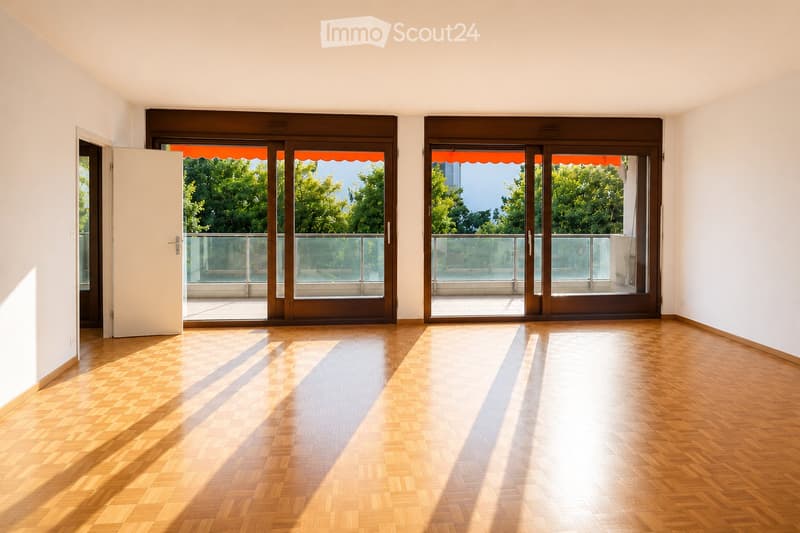 Empty room with wooden flooring, large sliding glass doors leading to a balcony, and white walls.