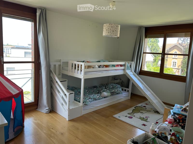 Brightly lit bedroom with a bunk bed, slide, toy tent, and various children's toys and items.