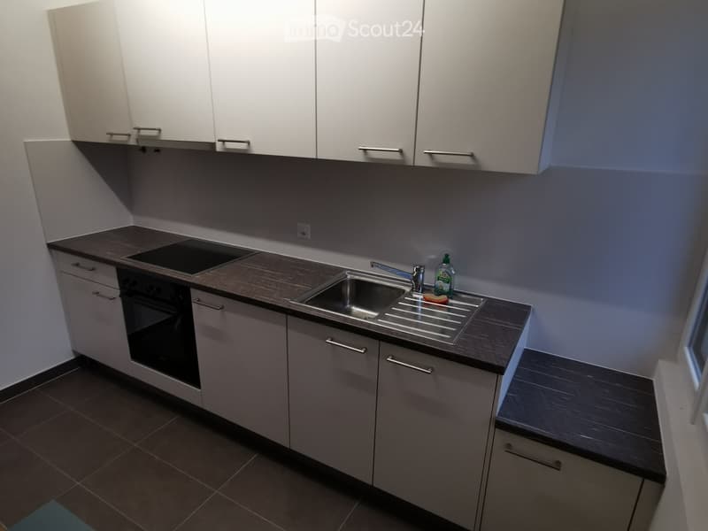Modern kitchen with white cabinets, dark countertops, and stainless steel sink.