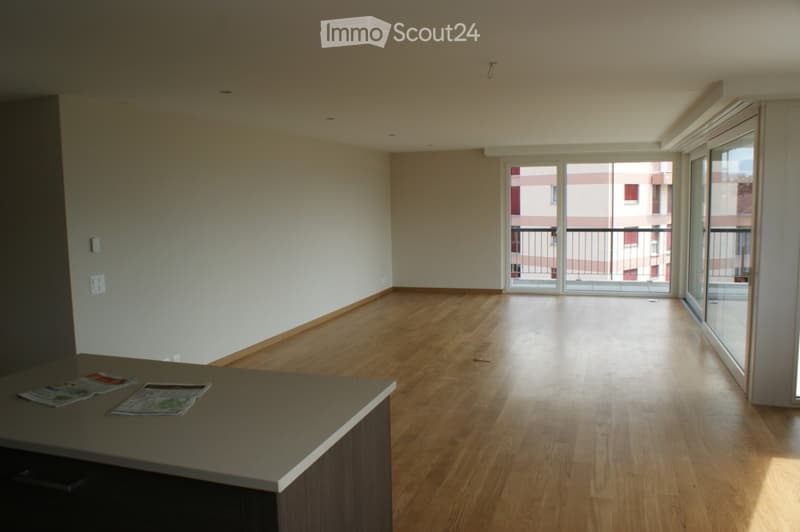 Empty room with wooden flooring, large windows, and a balcony access. No furniture or equipment present.