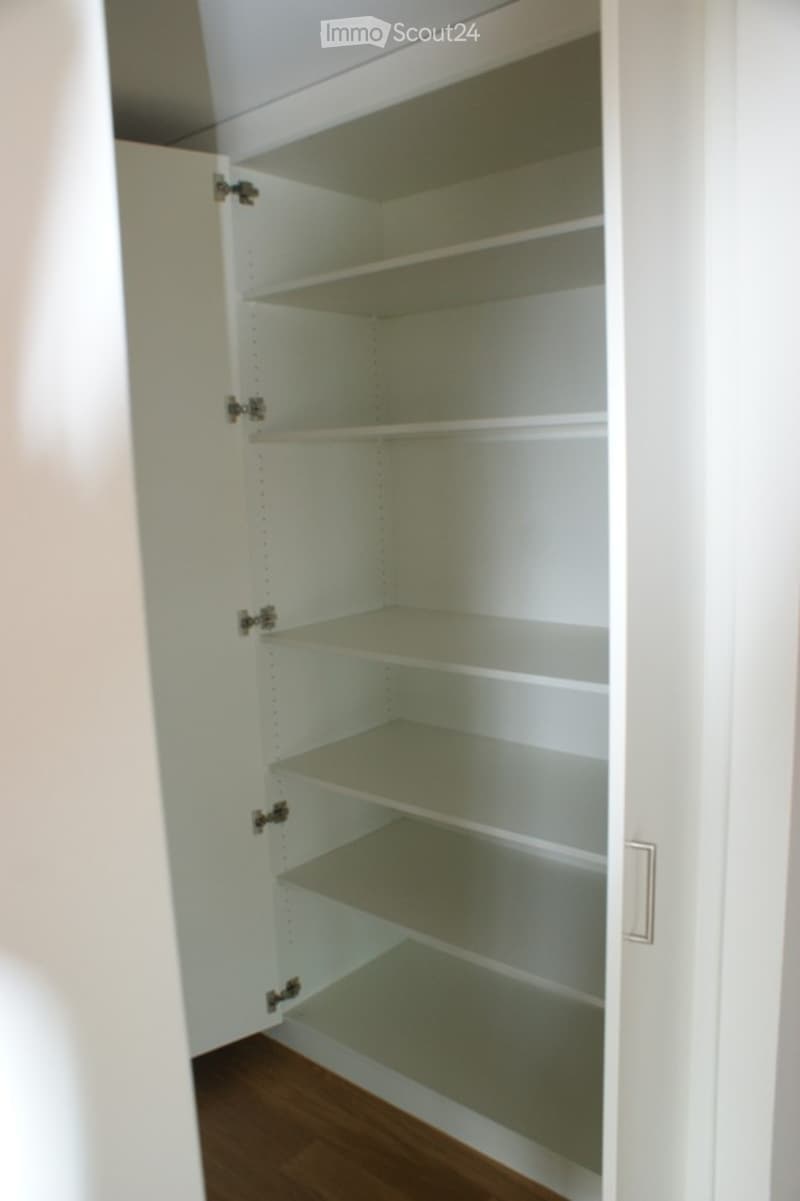 Empty white pantry with multiple shelves and a wooden floor.
