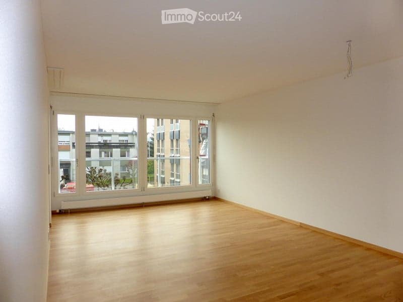 Empty room with wooden flooring, large windows, and white walls. No furniture or equipment present.