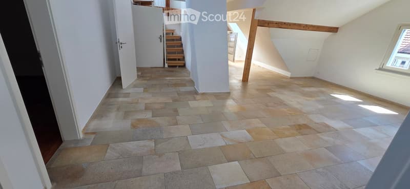 Empty hallway with tiled floor, white walls, and wooden staircase leading upwards.