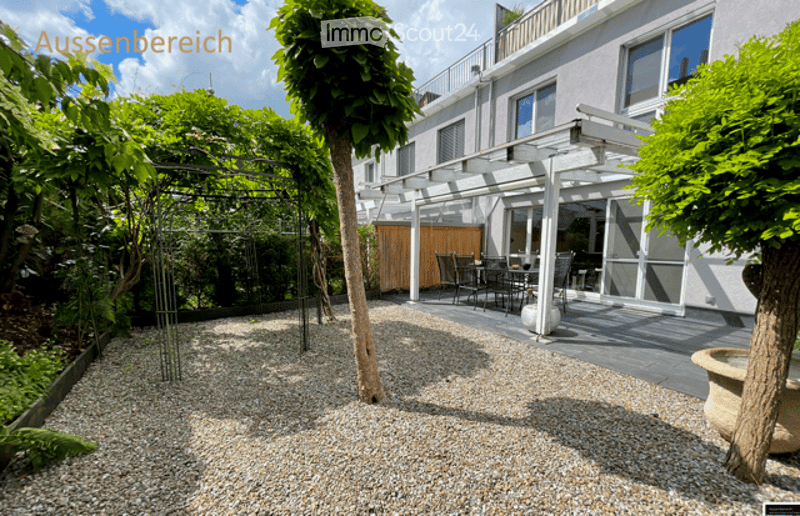Well-maintained garden area with gravel ground, trees, and a covered patio with outdoor furniture.