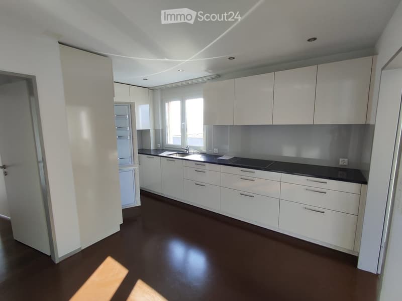 Modern kitchen with white cabinets, dark countertops, and a black floor. Features a sink, faucet, and stove.