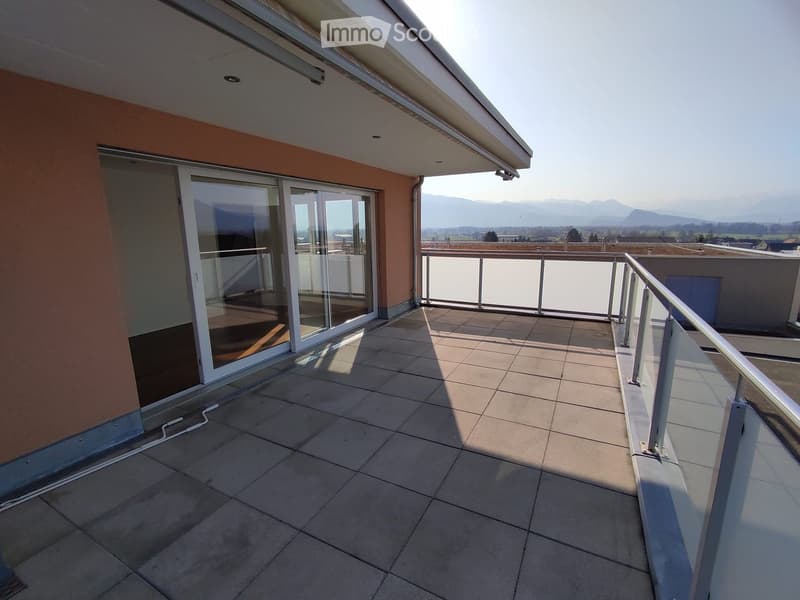 Balcony with tiled floor, glass sliding doors, and a glass railing, overlooking a scenic mountain view.