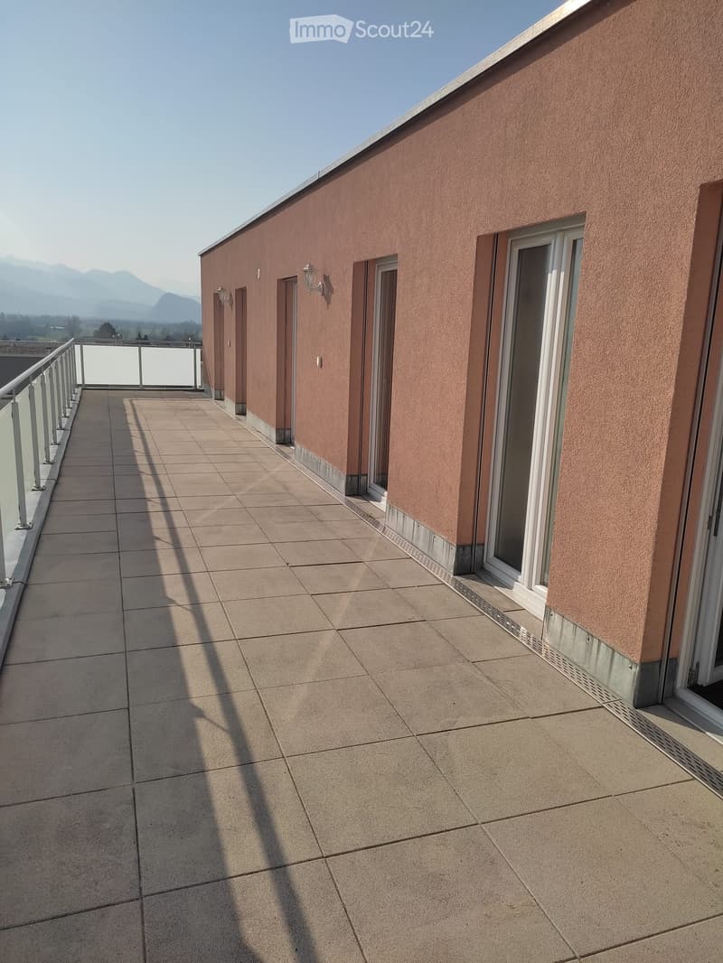 Balcony with tiled floor, glass railing, and scenic mountain view.