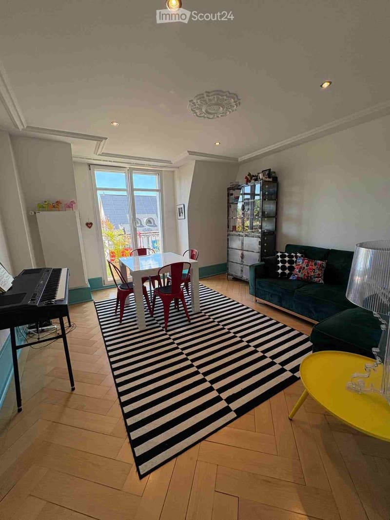 Living room with a green sofa, white dining table with red chairs, black piano, yellow coffee table, and a black and white striped rug.
