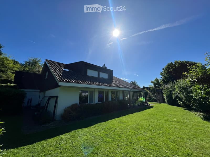 Two-story house with a tiled roof, large windows, and a well-maintained lawn in the front yard.