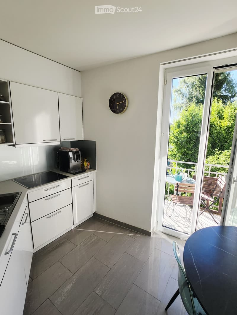 Modern kitchen with white cabinets, stainless steel appliances, and a sliding glass door leading to a balcony.