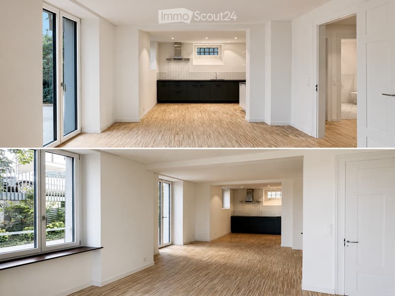 Bright, open-plan living and dining area with light wooden flooring, white walls, large glass doors leading to a balcony, and a modern kitchen with black cabinets and stainless steel appliances.