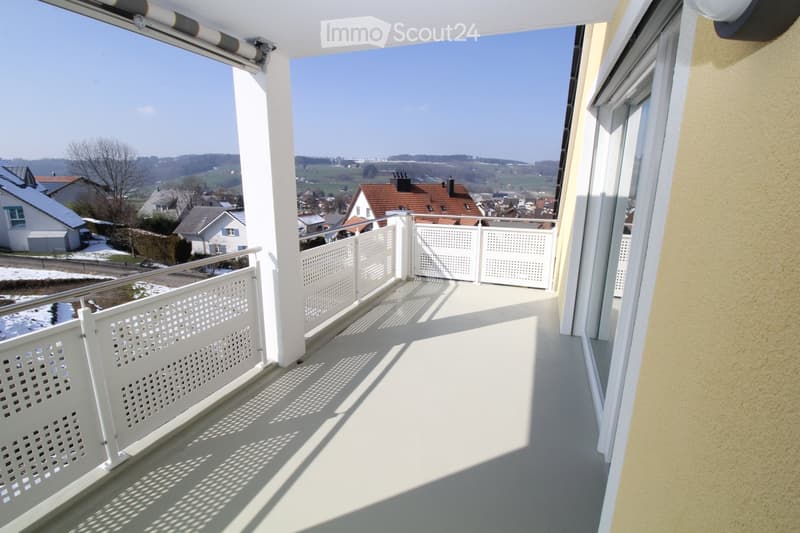 Modern balcony with white railings and floor, offering a panoramic view of the surroundings.