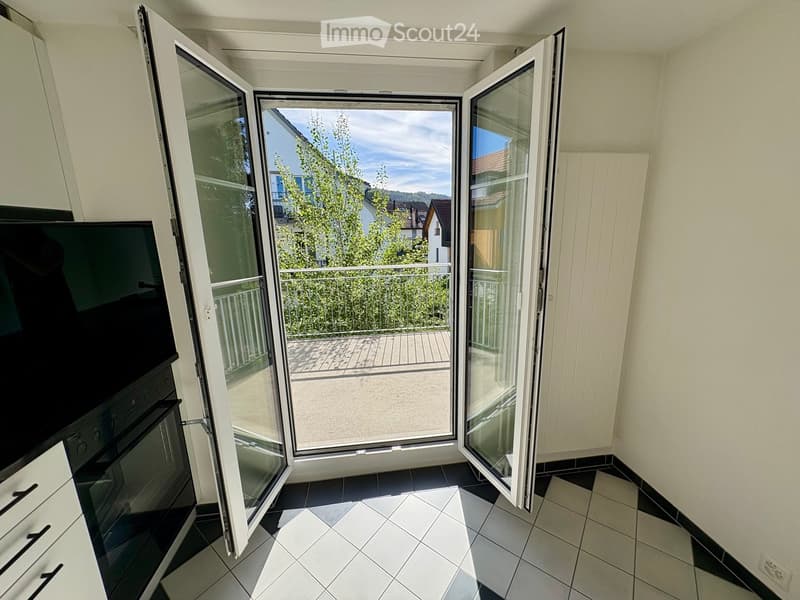Modern room with large sliding glass doors opening to a balcony, tiled floor, oven, and screen.