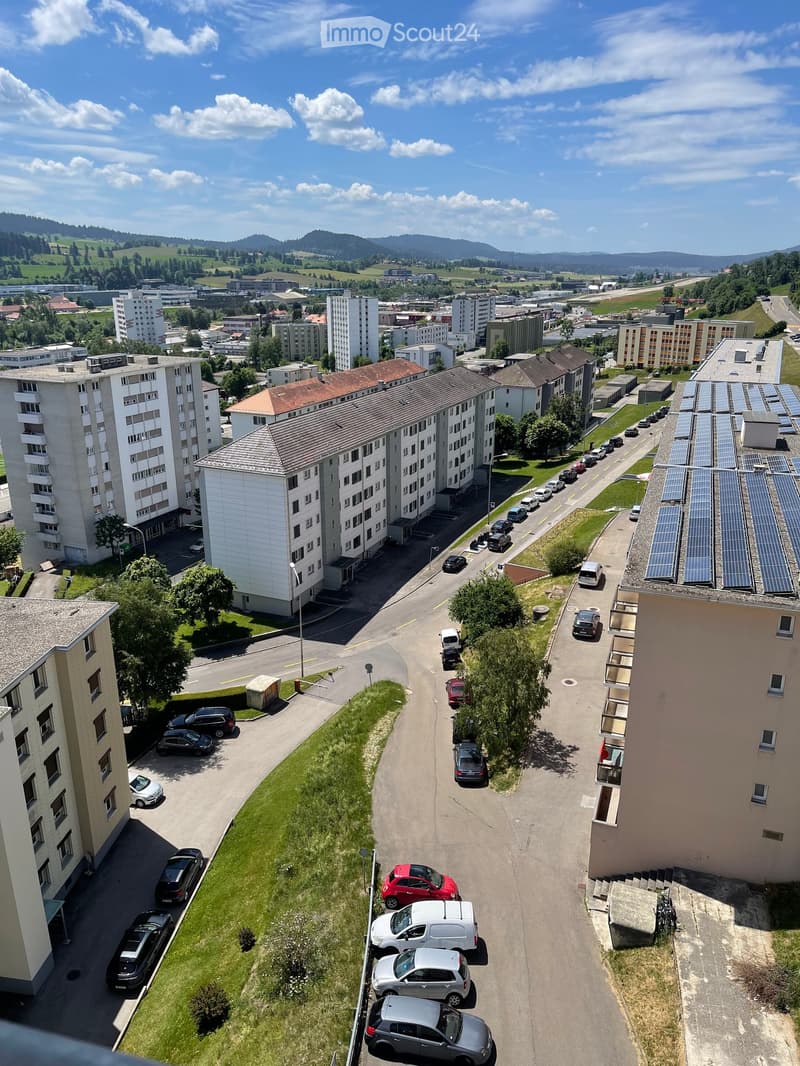 Aerial view of a residential area with multiple apartment buildings, parking lots, and surrounding greenery.