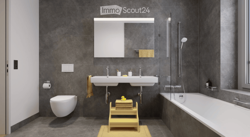 Modern bathroom with dark grey tiles, white toilet, double sink, bathtub, mirror, and a small wooden stool with towels and a rubber duck.